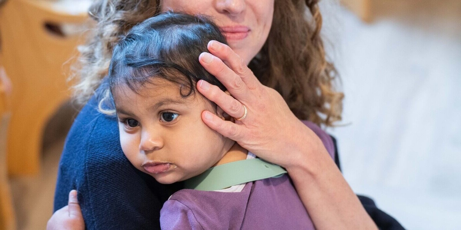 Baby cuddles daycare teacher