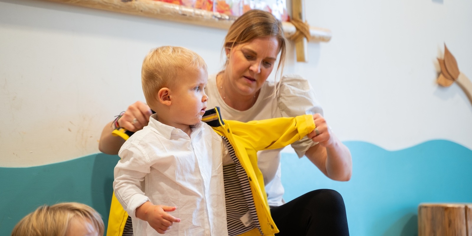 Basker daycare practitioner puts jacket on child