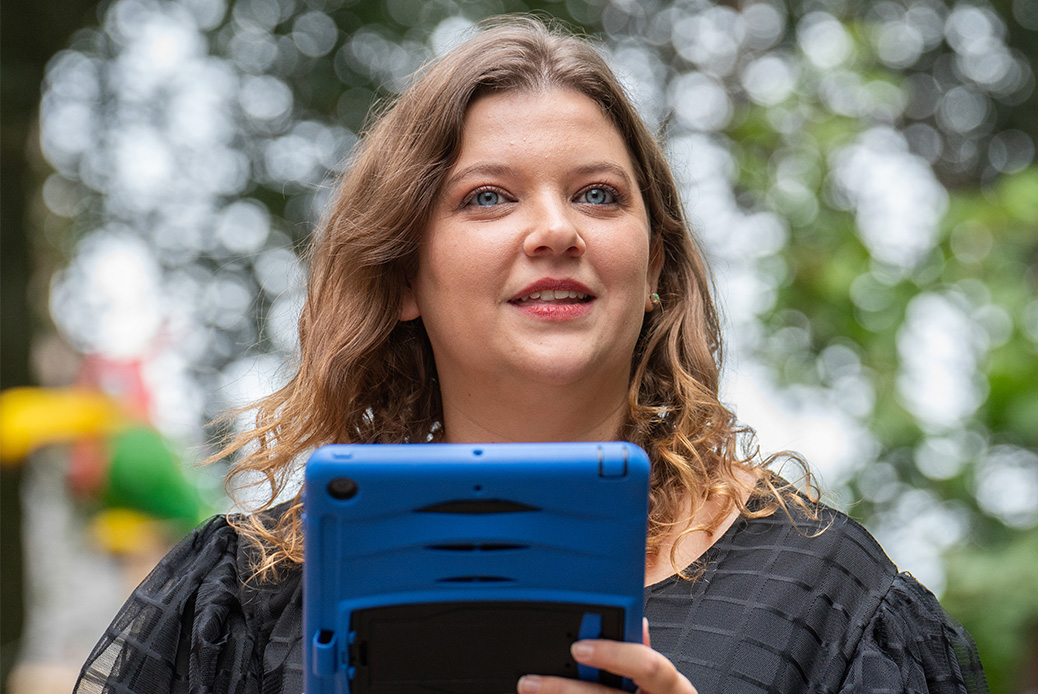Woman holding an ipad with the Holiday Camps schedule on it