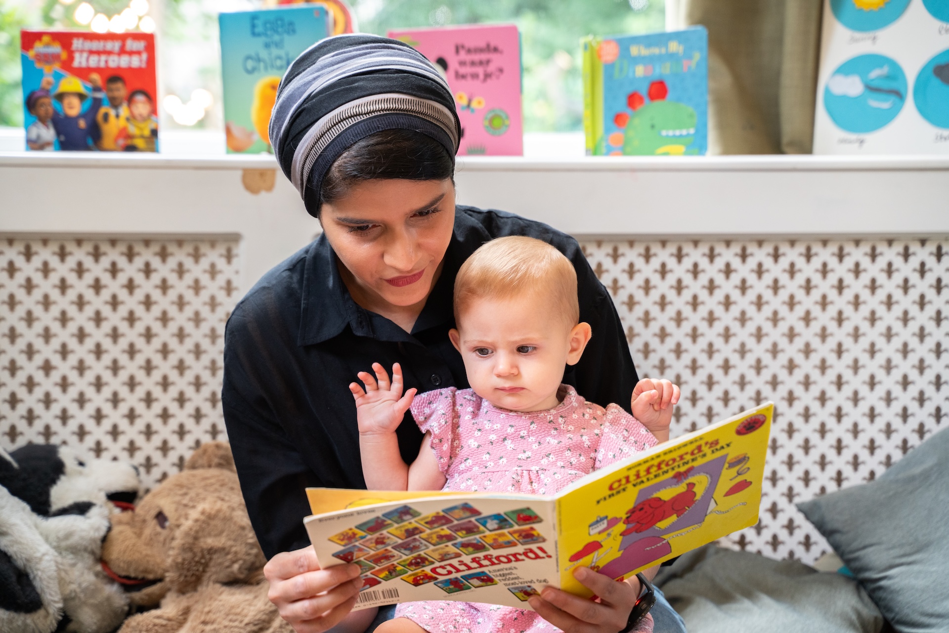 Childcare teacher reads book to baby