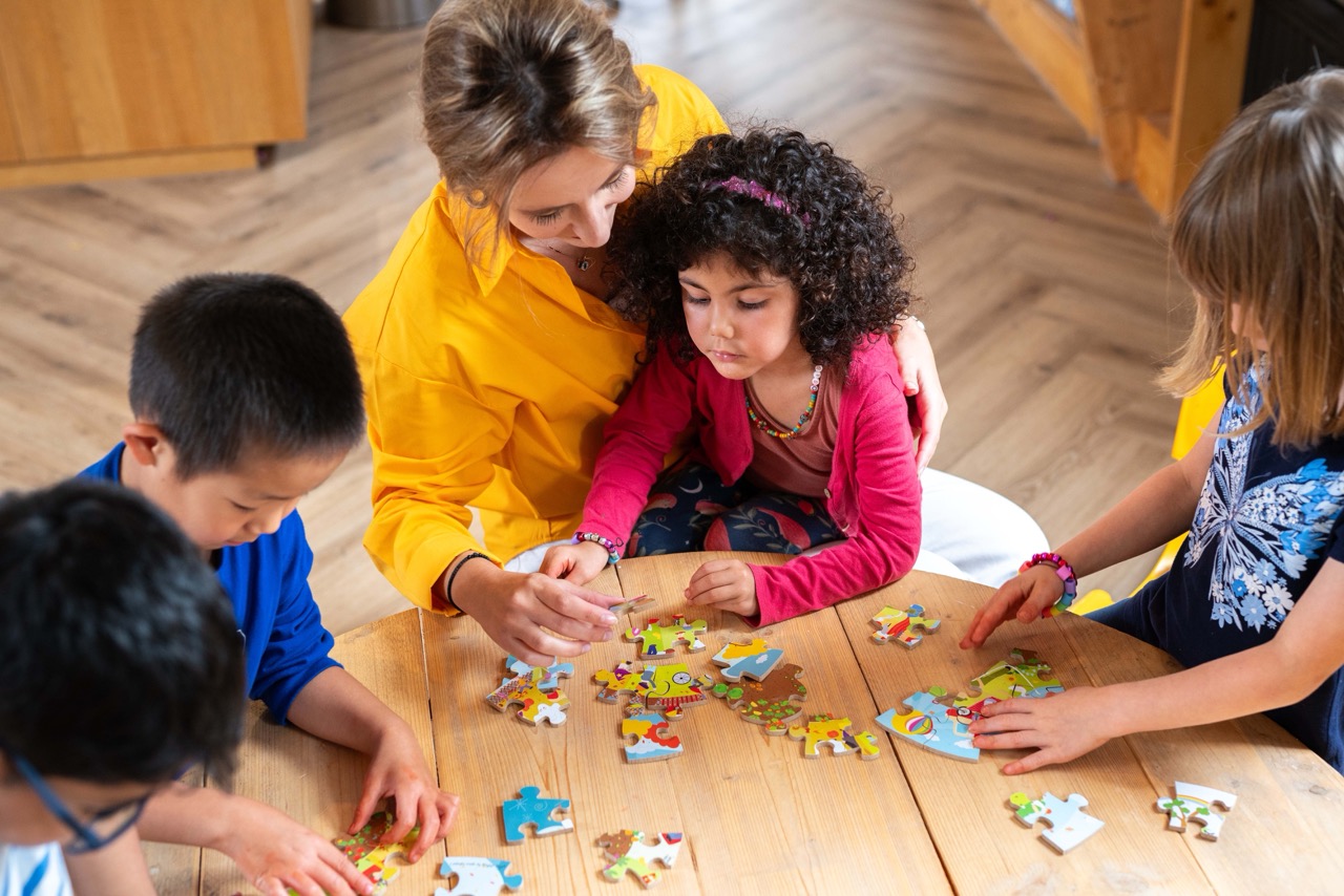 Pedagogic professional and children doing a puzzle