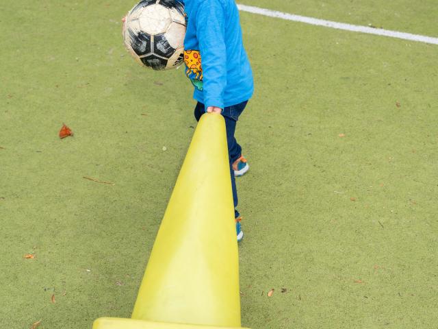 Child with ball and pylon
