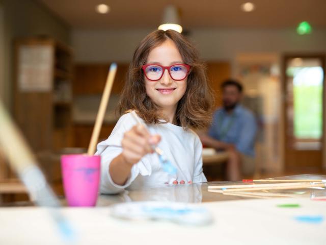 Girl with glasses painting at After School Care
