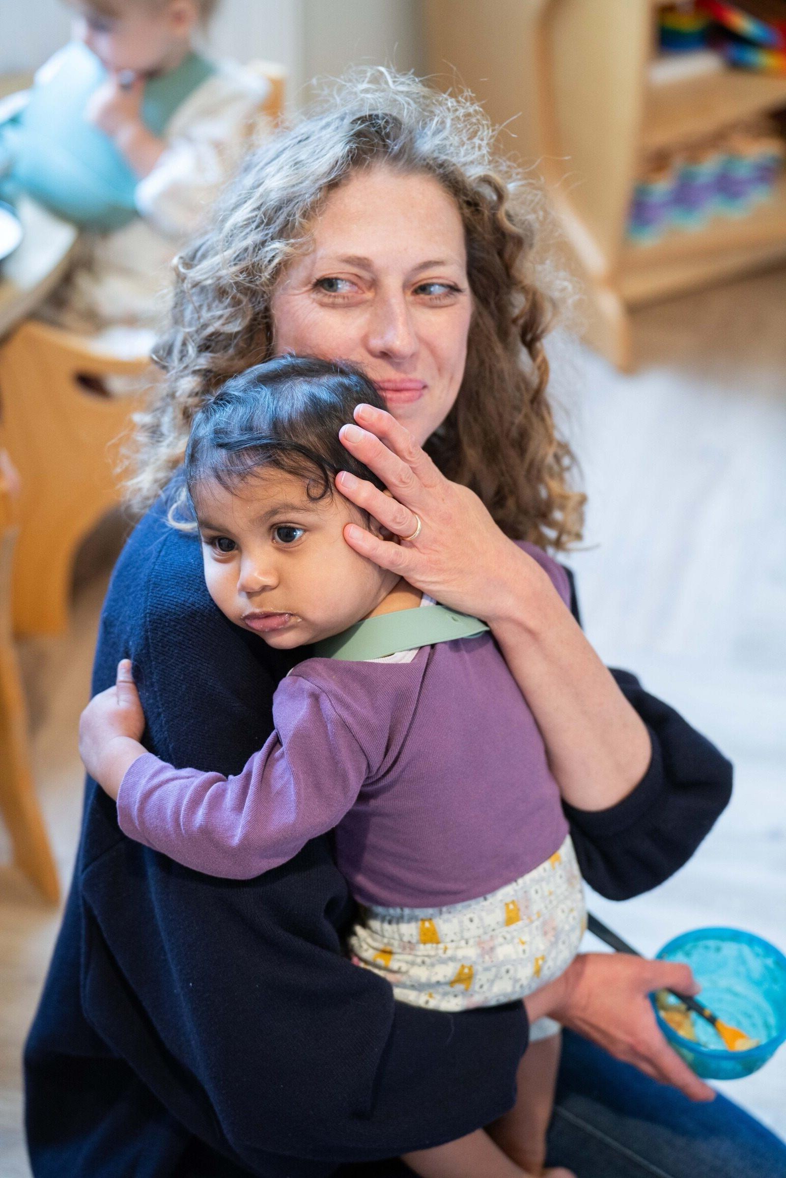 Basker International Childcare teacher cuddles baby