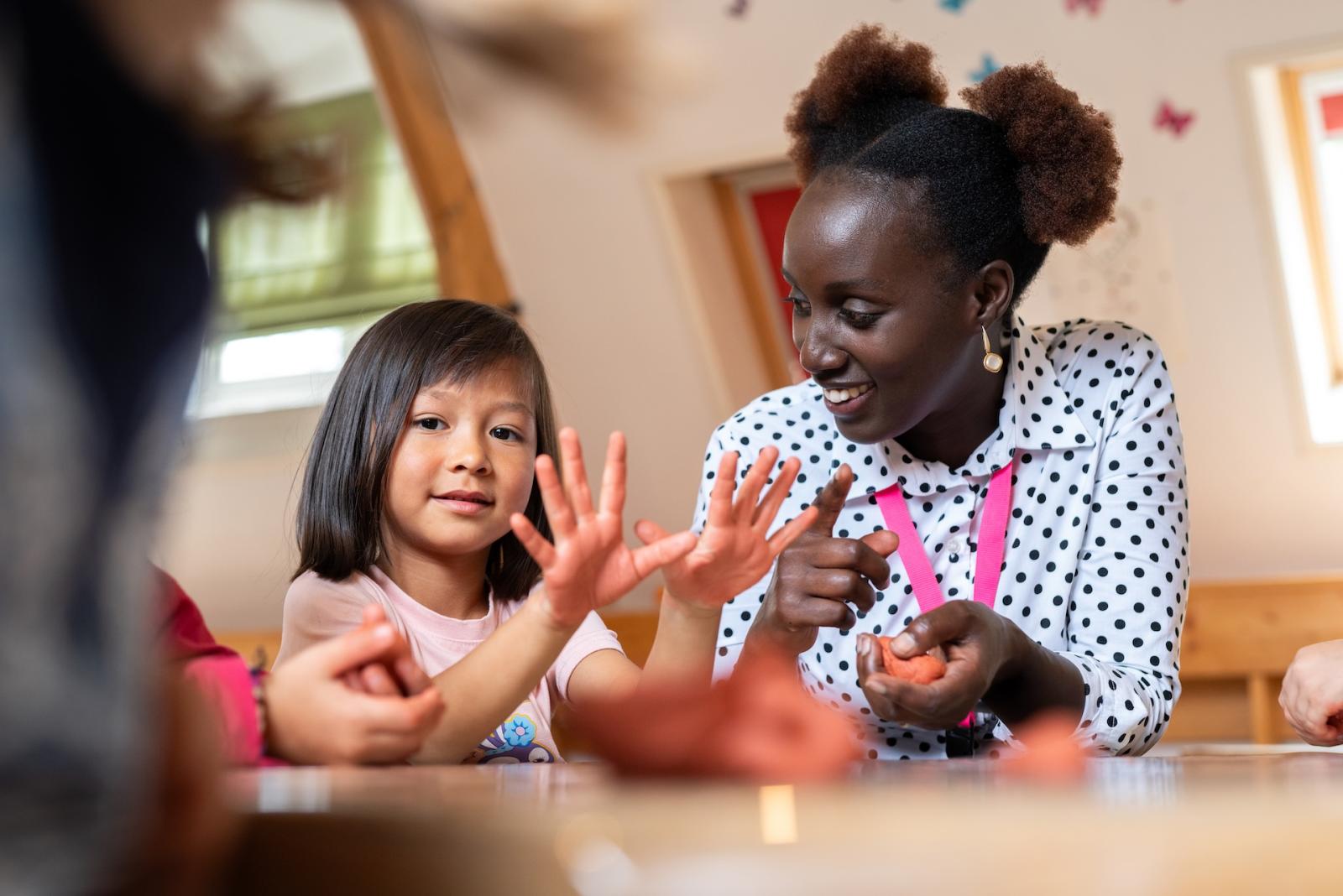 Child and teacher play with clay at Basker Childcare