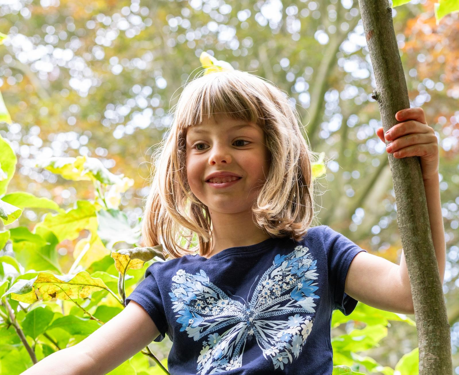 Child sits in tree at Basker International Childcare