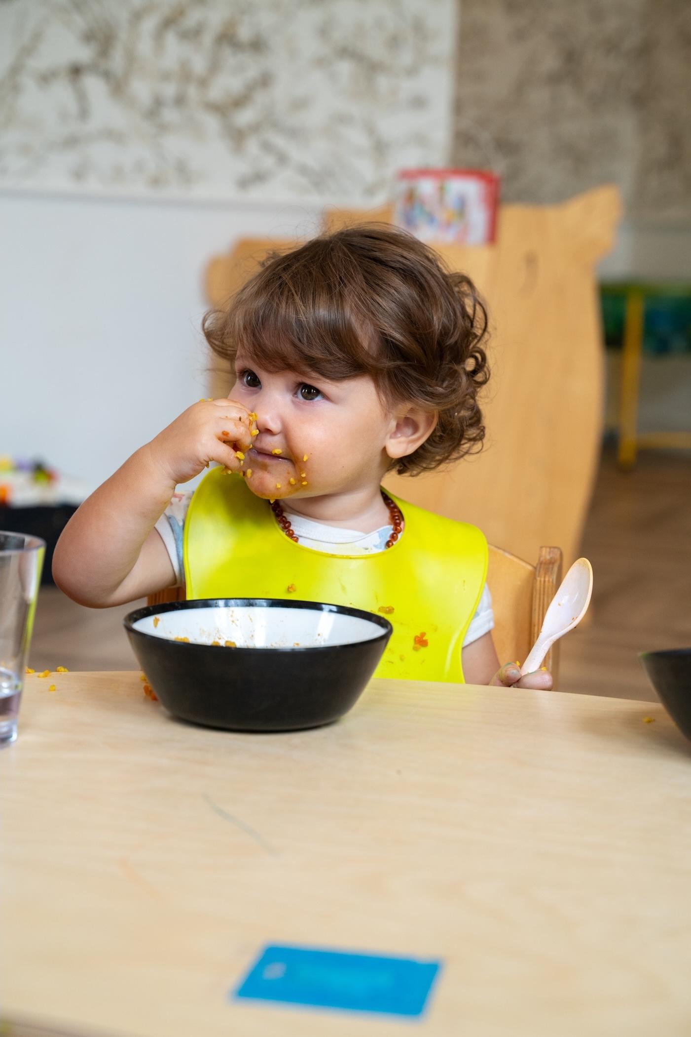 Little girl eating food at Basker International Childcare
