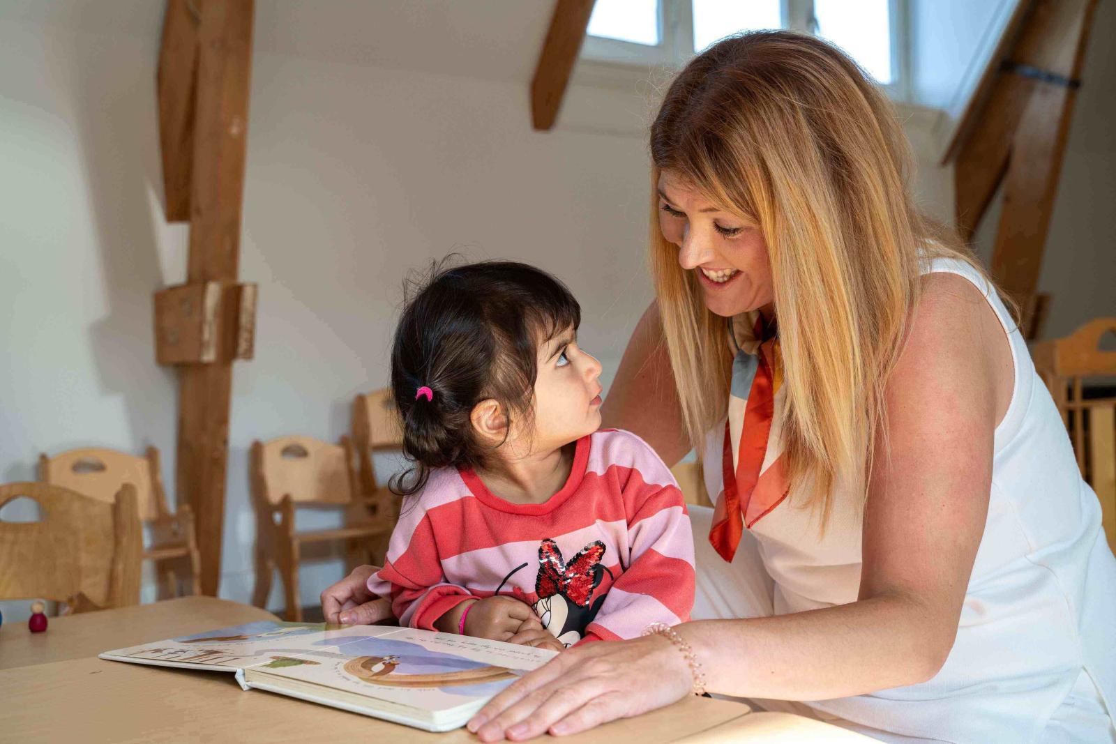 Teacher at Basker Childcare reads book with child
