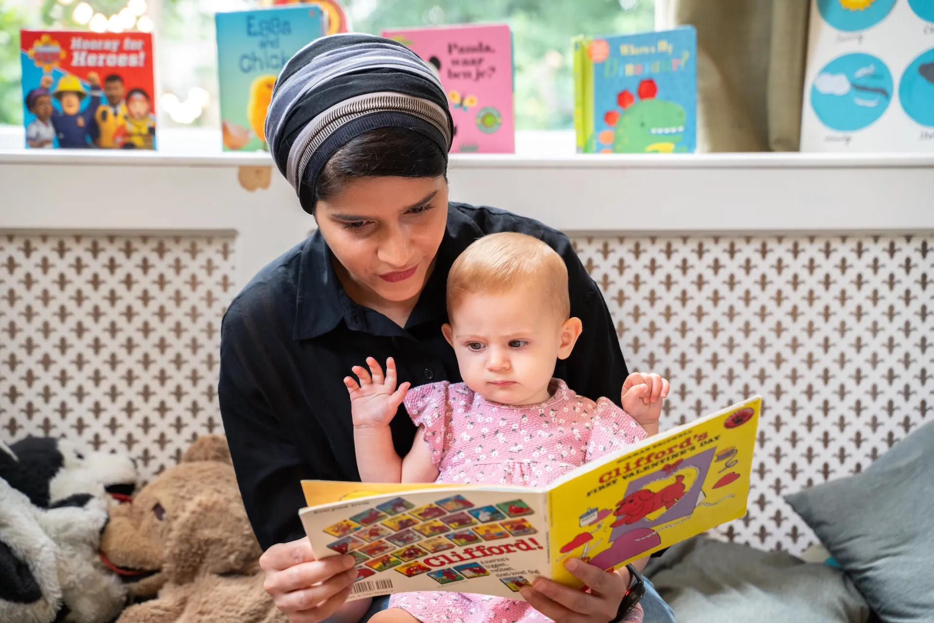 Basker daycare teacher reads a book to baby